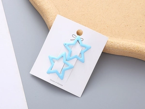 Détail de deux pinces à cheveux en forme d'étoile bleu clair sur carte blanche mate