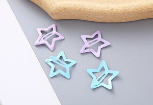 Détail de quatre barrettes en forme d'étoile en métal violet pastel et bleu ciel mat