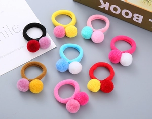 Close-up of 8 colorful plush ball hair ties in various candy colors for girls