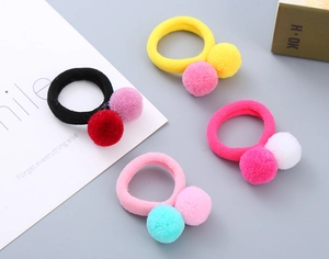 Detail of four high-elastic hair ties with colorful fuzzy pom-pom balls for girls