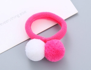 Detailed macro view of pink elastic hair tie with soft white and pink plush pom-pom balls
