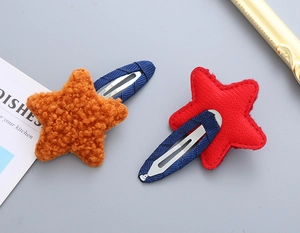 Detail von sternförmigen Haarspangen mit orangefarbenem Plüsch und rotem gestepptem Stoff