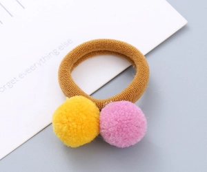 Detailed view of brown elastic hair ties with yellow and pink soft plush balls for girls