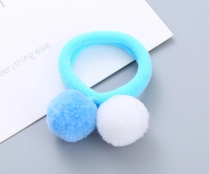 Close-up of light blue elastic hair tie with soft light blue and white plush pom-poms