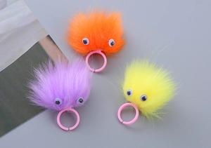 Close-up of colorful plush monster rings for kids with fuzzy textures and plastic bases