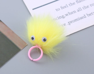 Close-up of a cute yellow plush monster ring with big eyes and a pink plastic band