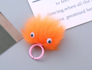 Detail of cute orange plush monster ring with fuzzy fur and adjustable pink band
