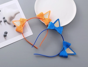 Dettaglio di cerchietti con orecchie da gatto glitterate in arancione e blu reale