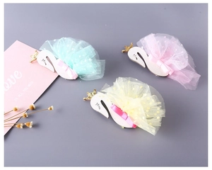 Detailed view of swan hair clips with mesh skirts, golden crowns and ribbons in three colors