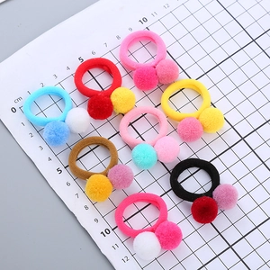 Set of 7 colorful pom-pom elastic hair ties for girls on a white measurement scale