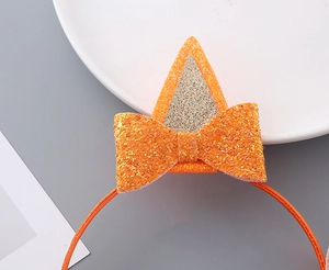 Dettaglio cerchietto con orecchie di gatto in paillettes arancioni e fiocco per bambina