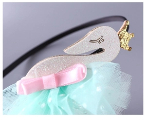 Close-up of glittery swan crown and mint green polka dot mesh on children's headband