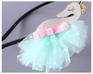 Close-up of a swan headband featuring a gold crown and mint green polka dot mesh skirt