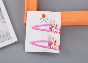 Detalle de pinzas para el pelo de unicornio rosa con purpurina en tarjeta de cartón