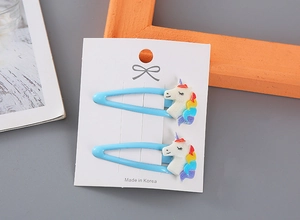 Vista detallada de dos pinzas para el pelo de unicornio azul claro en cartón decorativo