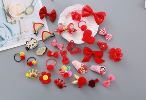 Close-up of red festive hair accessories including bows and plush balls in a ceramic dish