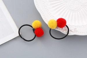 Detail of red and yellow plush ball hair clips with elastic bands for kids