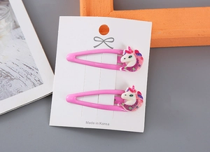 Detalle de pinzas de pelo de unicornio rosa con purpurina para niñas en cartón blanco