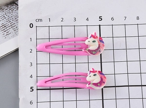 Detalle de dos pinzas para el pelo de unicornio rosa de 5 cm sobre una regla