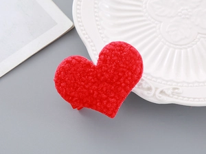 Detail view of heart-shaped red lamb wool hair clip with soft textured fabric surface