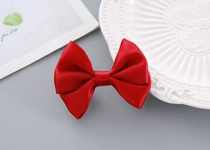 Detailed close-up of a vibrant red satin bow hair clip with smooth silky texture