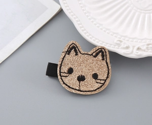 Close-up of a sparkling gold cat hair clip for children with detailed black embroidery