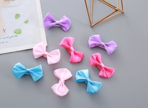 Close-up of eight satin bow hair clips in purple, rose, pink and blue colors