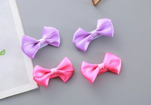 Detail of pink and purple satin bow hair clips with fully fabric-covered duckbill clips