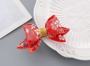 Detailed view of red bow hair clip with gold thread on white decorative porcelain plate