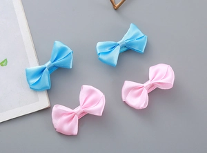 Detailed close-up of handmade satin bow hair clips in pastel pink and sky blue colors