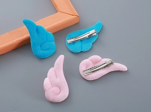 Detailweergave van pluche engelenvleugel haarclips in blauw en roze met metalen eendenbekclips