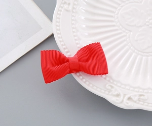 Macro shot of red ribbed festive bow hair clip on white porcelain for New Year