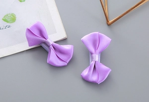 Detailed close-up of double-layered purple polyester bow hair clips on grey background
