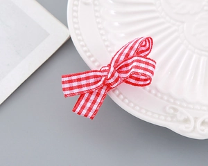 Detailed view of a red and white striped ribbon bow hair clip on a ceramic plate