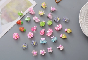 Close-up of colorful glitter resin accessories with crown and flower motifs on metal clips