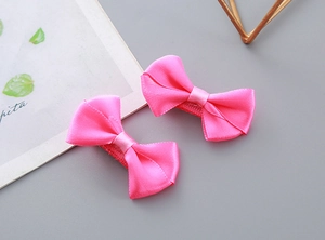 Detail of handmade bright pink satin bow hair clips with silk texture for children