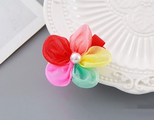 Close-up of mesh flower hair clip with white faux pearl and red ribbon base