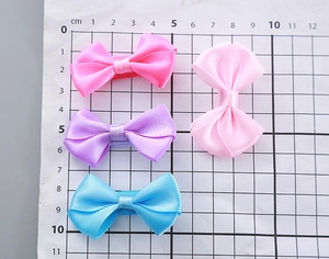 Detailed view of handmade polyester bow hair clips in four colors on a grid measuring mat