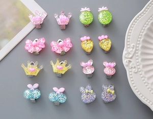 Detailed flat lay of colorful resin clip-on earrings for kids featuring glitter crown shapes