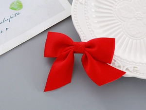 Detail of red satin bow hair clip with long ribbons on a white decorative plate