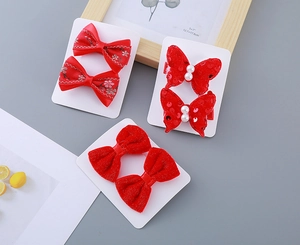 Detailed close-up of three pairs of festive red velvet and sequin bow hair clips for girls