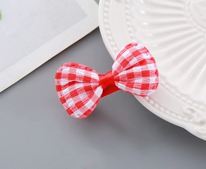 Close-up of red and white gingham bow hair clip on a white decorative porcelain plate