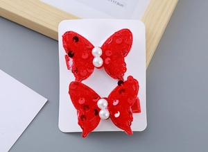 Close-up of red sequined bow hair clips with white pearls for girls New Year festive style