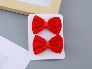 Detail view of two red flocked hair clips with silver glitter bows for girls' New Year
