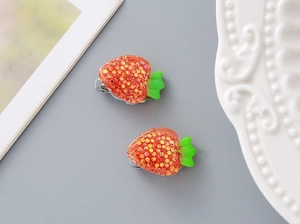 Detail of red glitter strawberry clips with green leaves on a white porcelain dish