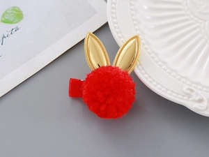 Detailed view of a red plush rabbit hair clip with gold bunny ears on a stylish background