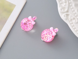Close-up of pink glitter resin ear clips with cute bow for girls with no piercings