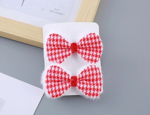 Detail of red houndstooth bow hair clips with white faux fur trim and glitter centers