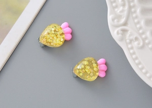 Close-up of cute strawberry resin hair clips with golden glitter and pink leaves