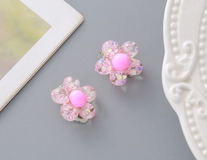 Close-up of pink resin flower clip-on earrings with glitter filler for little girls